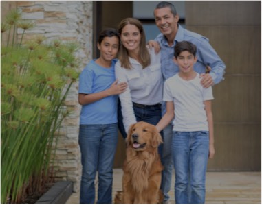 Family of 4 standing in front of their house with a dog