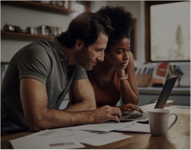 Couple sitting at a table looking at a laptop